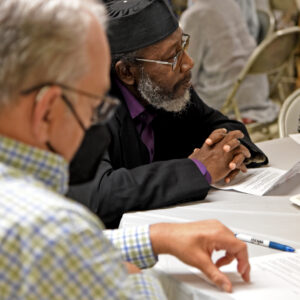 Imam Shafeeq Sabir, center, listens to the discussion at Teatime for Peace, an interfaith dialog for the members of  Masjid Bilal of Cleveland and the Community of Saint Peter, at the Masjid Bilal in Cleveland, Saturday, July 16, 2022. (Photo by Peggy Turbett.)